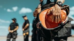 A firewatch guard holding a helmet.