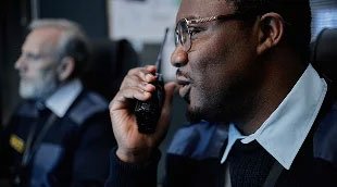 A security guard speaking on a radio.