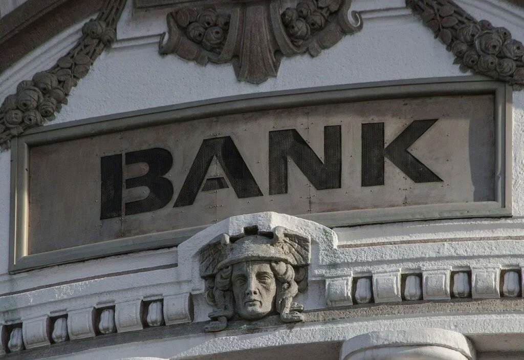 Ornate stone facade of a historic bank building with "BANK" sign and carved face detail.