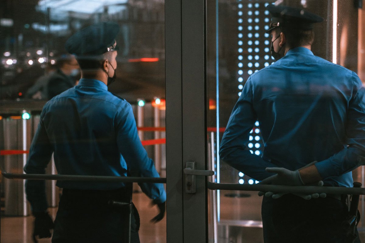 Security guards standing by glass doors, protecting a hotel entrance at night.
