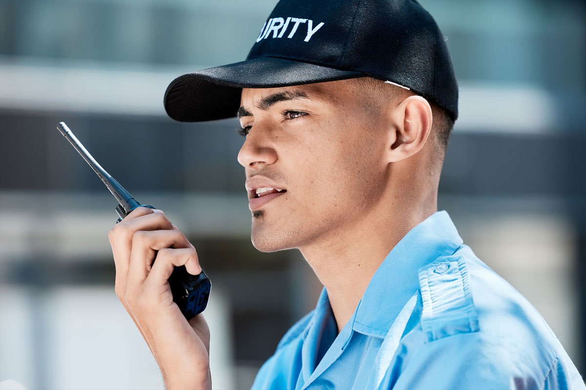 A young security guard communicates on a walkie talkie.