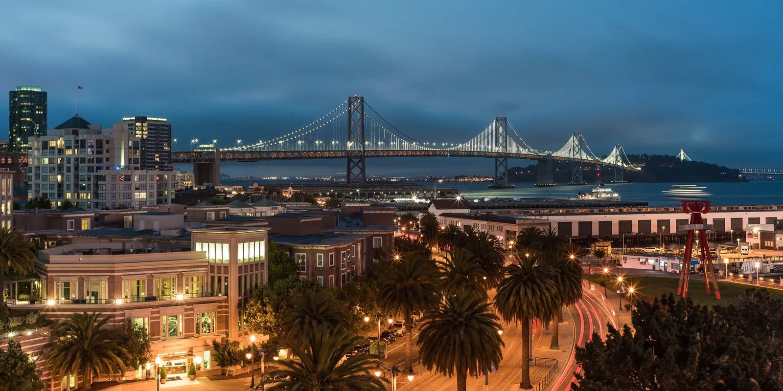 Kern County Downtown San Francisco skyline at dusk with the Bay Bridge lit up.