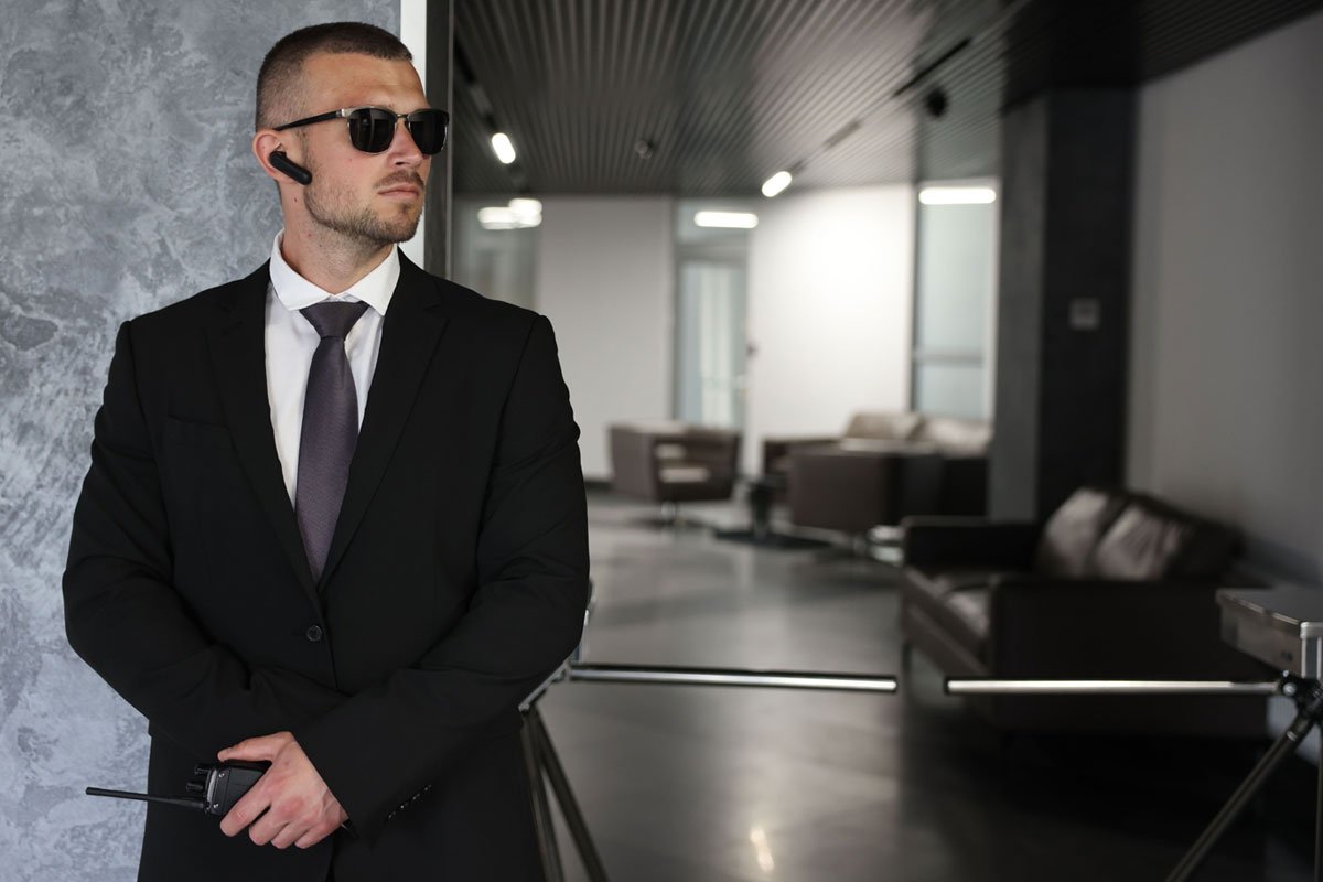 A professional security guard stands alert at the entrance of a contemporary office lobby.